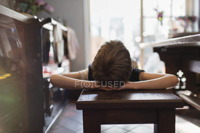 Boy relaxing on bench in kitchen — Stock Photo