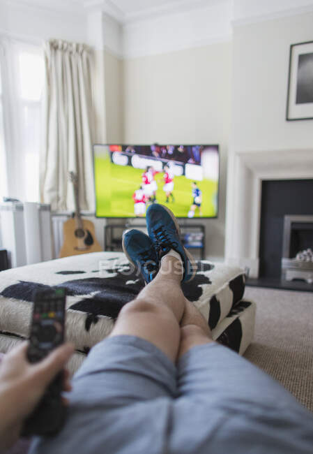 POV man watching soccer match on TV in living room — Stock Photo
