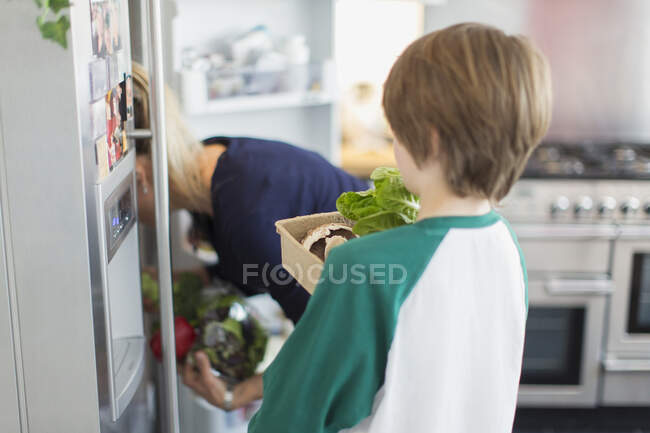 Mother and son with fresh vegetables in kitchen — Stock Photo