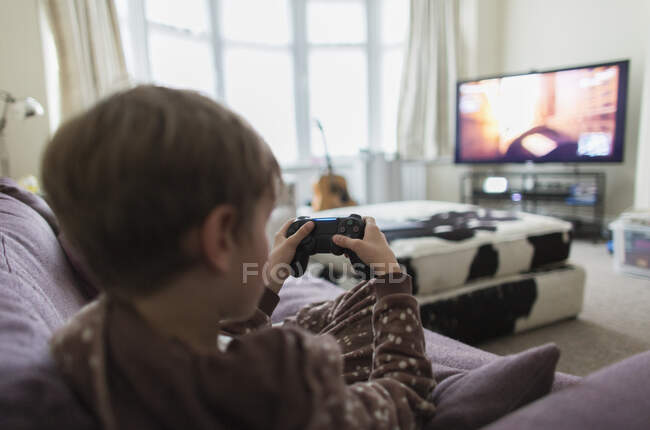 Garçon jouer jeu vidéo sur canapé salon — Photo de stock