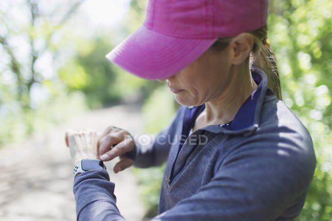 Female jogger with smart watch on hiking trail — Stock Photo