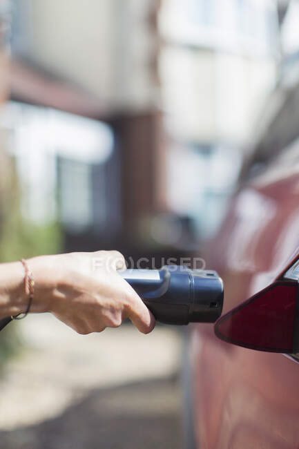 Закрыть женщину, подзаряжающую электромобиль — стоковое фото