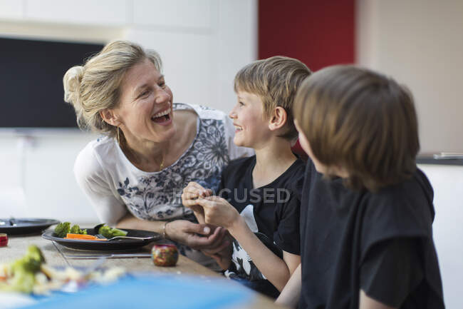 Happy mother and sons eating dinner at table — Stock Photo