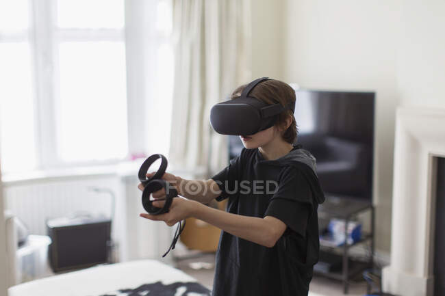 Niño jugando videojuego con gafas VRS en la sala de estar - foto de stock