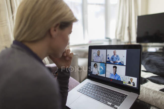 Mujer vídeo chat con los médicos en el ordenador portátil desde casa - foto de stock