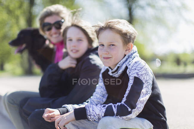 Portrait mother and sons with dog in sunny park — Stock Photo