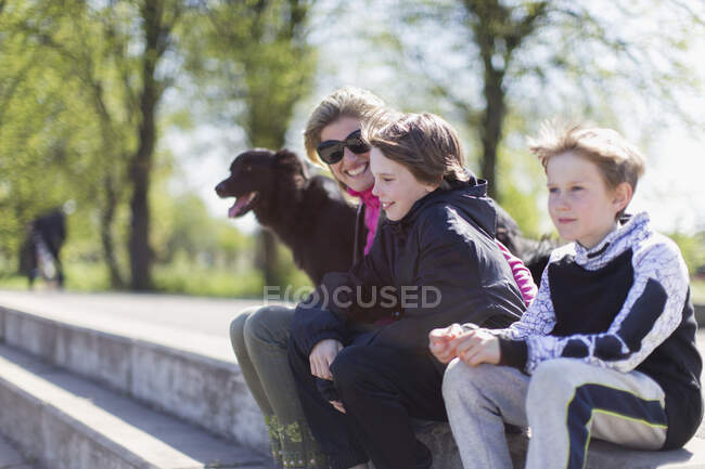 Glückliche Mutter und Söhne mit Hund im sonnigen Park — Stockfoto