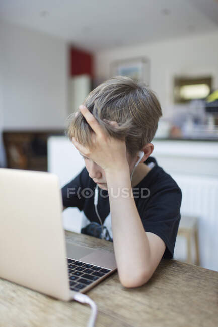 Boy with headphones homeschooling at laptop — Stock Photo