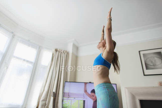 Mulher praticando ioga online na sala de estar — Fotografia de Stock