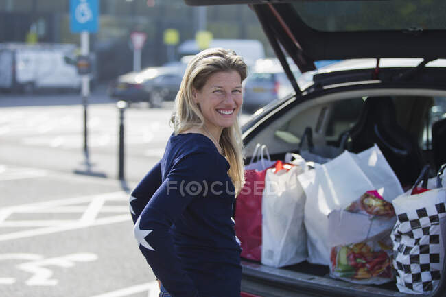 Portrait happy woman with grocery bags at bag of car — Stock Photo