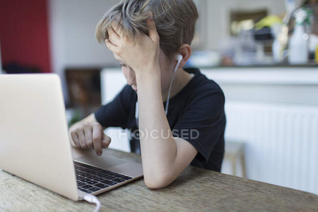 Frustrado menino com fones de ouvido homeschooling no laptop — Fotografia de Stock