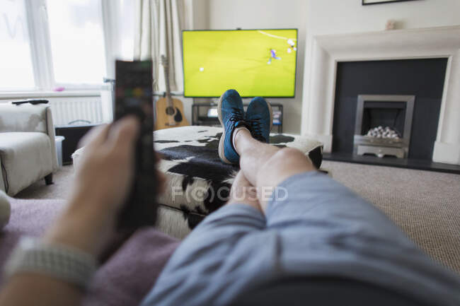 POV homem no sofá com controle remoto assistindo jogo de futebol na TV — Fotografia de Stock