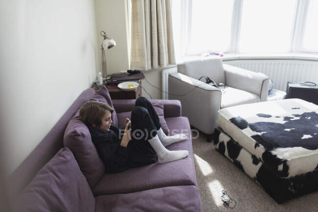 Menino usando telefone inteligente no sofá da sala de estar — Fotografia de Stock