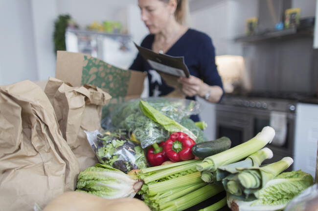 Woman unloading fresh produce from box in kitchen — Stock Photo