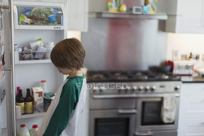 Garçon regardant à l'intérieur réfrigérateur cuisine — Photo de stock