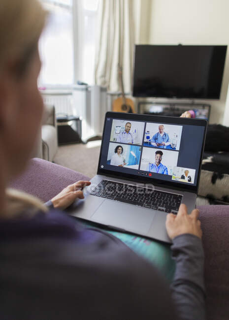 Woman video chatting with doctors at laptop from home — Stock Photo