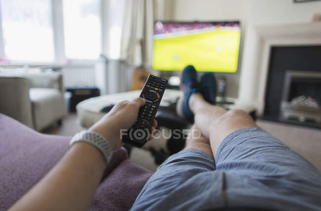 Uomo POV con telecomando che guarda partita di calcio sul divano del salotto — Foto stock