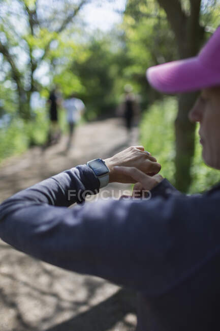 Woman with smart phone jogging on trail in park — Stock Photo