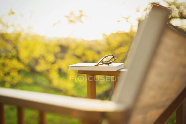 Book and eyeglasses on lawn chair in sunny garden — Stock Photo