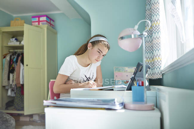Окаменелая девочка учится на дому в спальне — стоковое фото