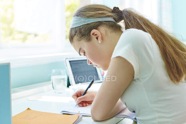 Focalizzata Ragazza che fa i compiti alla scrivania — Foto stock