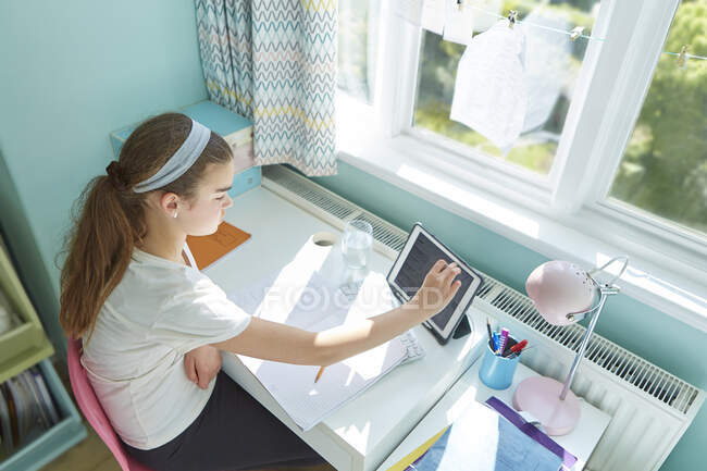 Menina com tablet digital homeschooling na mesa no quarto ensolarado — Fotografia de Stock