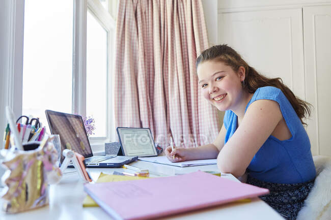 Retrato confiante menina homeschooling na mesa no quarto — Fotografia de Stock