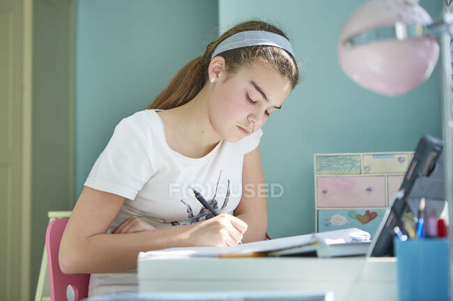 Девочка делает домашнее задание в спальне — стоковое фото