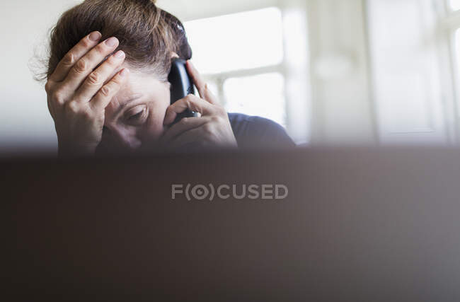 Втомилася жінка розмовляє по телефону на ноутбуці — стокове фото