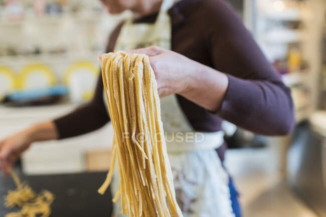 Mujer haciendo pasta casera fresca en la cocina - foto de stock