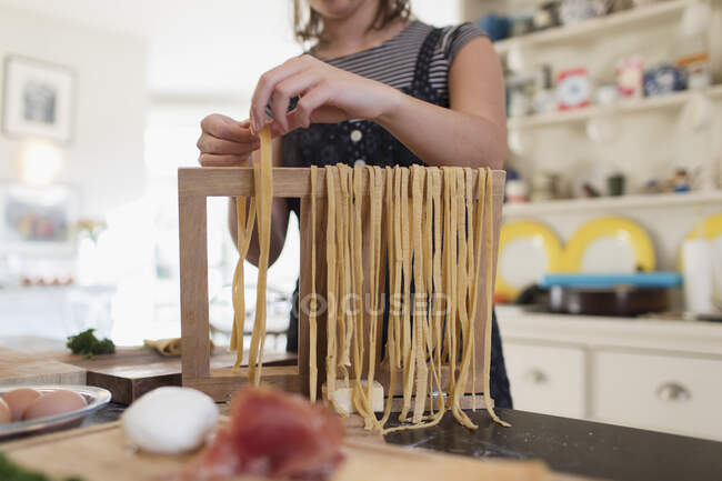 Девочка-подросток готовит свежую домашнюю пасту на кухне — стоковое фото