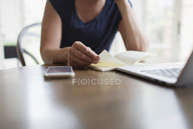 Woman with notebook working from home at laptop — Stock Photo