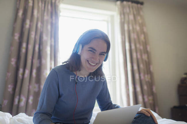 Retrato menina adolescente feliz com fones de ouvido e tablet digital na cama — Fotografia de Stock