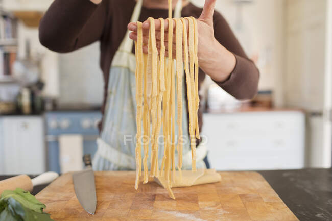 Cerca de la mujer haciendo pasta fresca casera en la cocina - foto de stock