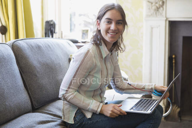 Портрет усміхненої дівчини-підлітка, що використовує ноутбук на дивані — стокове фото