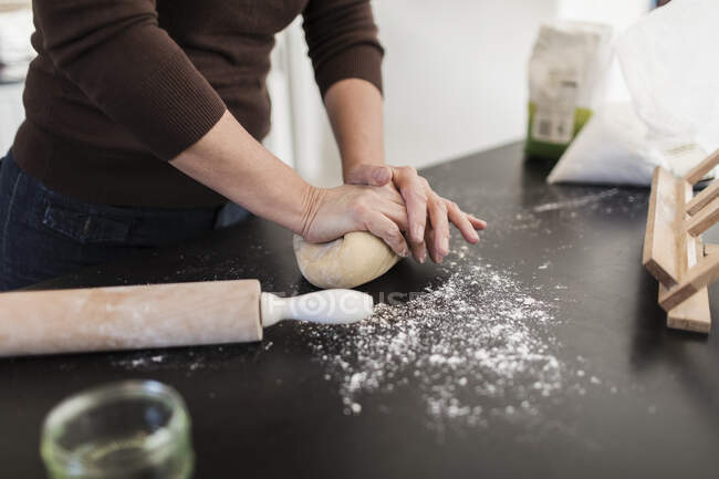 Женщина разминает тесто на кухонном столе — стоковое фото