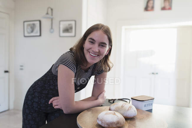 Portrait happy teenage girl with homemade baked bread in kitchen — Stock Photo