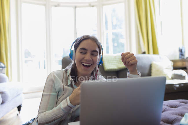 Happy teenage girl with headphones video chatting at laptop — Stock Photo