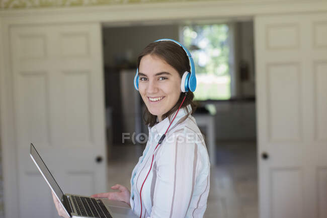 Portrait confident teenage girl with headphones and laptop — Stock Photo