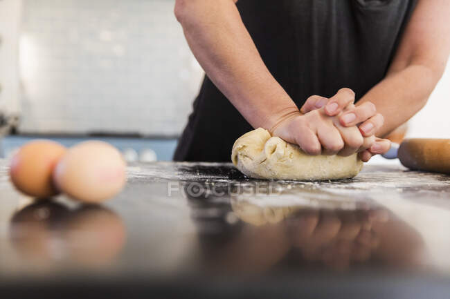 Закрыть женщину смешивая тесто на кухонном столе — стоковое фото