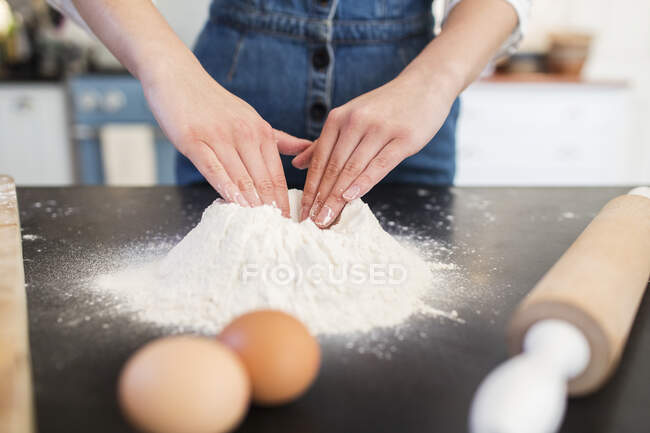 Close up teenage girl making flour nest on kitchen counter — Stock Photo
