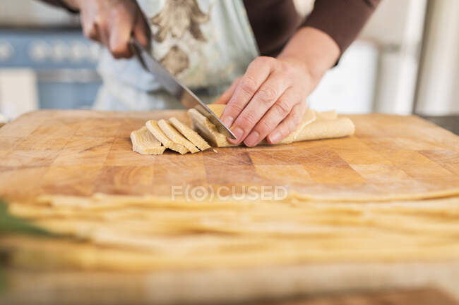 Fermer femme coupe pâte fraîche maison sur planche à découper — Photo de stock