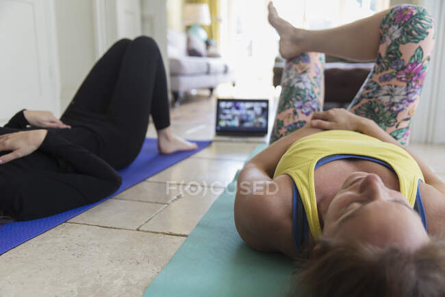 Madre e hija haciendo ejercicio en línea en casa con laptop - foto de stock