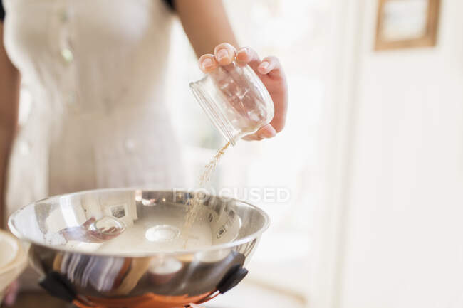 Крупним планом дівчина-підліток додає інгредієнт для випічки в миску — стокове фото
