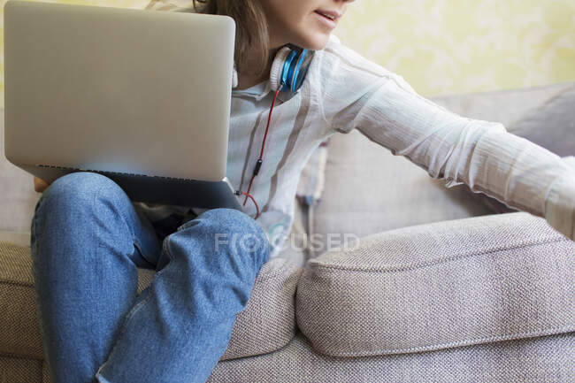 Chica adolescente con ordenador portátil en el sofá - foto de stock