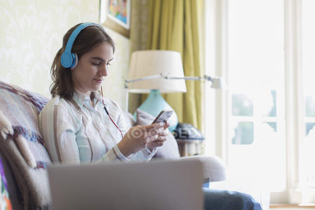 Teenagermädchen mit Kopfhörer und Smartphone auf Sofa — Stockfoto