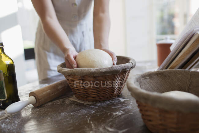 Mulher colocando massa em cesta de prova na cozinha — Fotografia de Stock