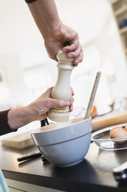 Donna macinare il pepe in ciotola in cucina — Foto stock