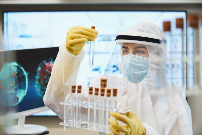 Женщина-ученый в чистом костюме исследует коронавирусную вакцину — стоковое фото