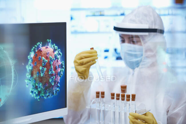 Scientifique en costume propre avec éprouvettes étudiant le coronavirus — Photo de stock